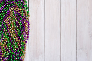 Mardi Gras beads on white wooden backgound © Elena_Bezzubtseva