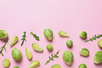 Fresh Brussels sprouts and arugula on color background, flat lay. Space for text