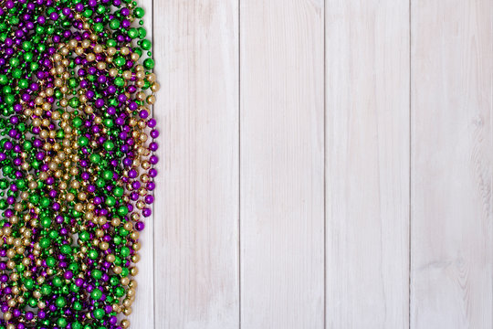 Mardi Gras beads on white wooden backgound
