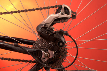 Rear derailleur of bicycle on red background - obrazy, fototapety, plakaty