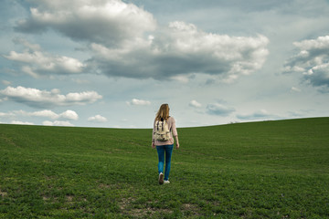 Traveler woman hiking in countryside, cloudy grey sky