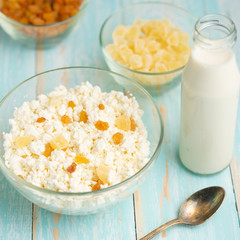 Cottage cheese with raisins and pineapple zucchini, with milk in a bowl on a blue wooden table