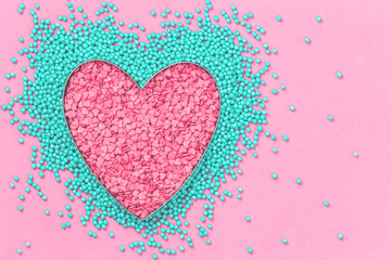 Pink and mint colors cake sprinkles sweets heart shape on pink background with copy space, flat lay. Love, Mother's and Valentines Day and charity concept