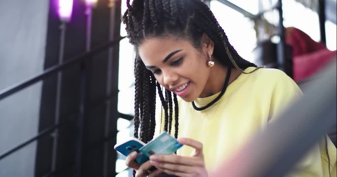 In a modern building office lady african ethnic order something online using her smartphone at the end she gesticulating with hand that she getting what she wants