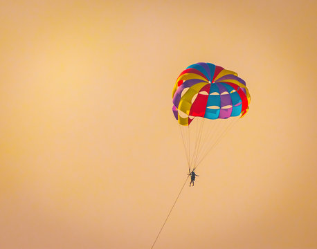 Parasailing on Baga Beach, Goa  in summer. person under parachute hanging mid air. Having fun. Tropical Paradise. Positive human emotions, feelings, family, travel, vacation.