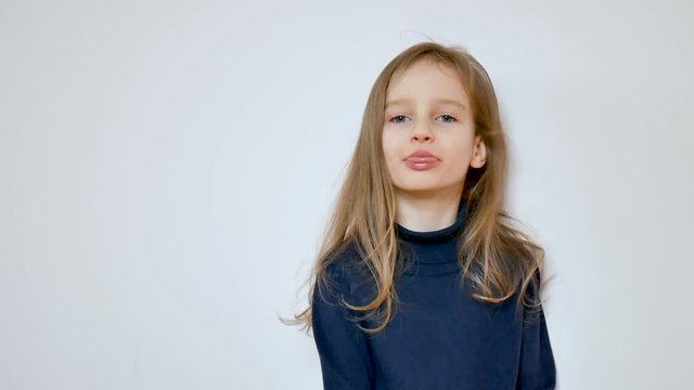 Close up video of cute girl with long blonde hair and big blue eyes grimacing while posing in the studio