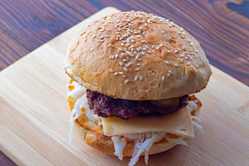 Homemade hamburger with fresh vegetables on a wooden background