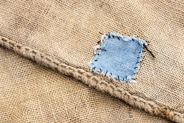 Fototapeta na wymiar Blue jeans patch on an old canvas bag. Close-up. 