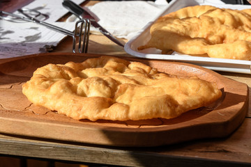Langos typical Hungarian food specialty, dish, deep fried dough on a wood table