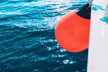 Coral yacht fender against dark sea. Boat trip and vacation concept