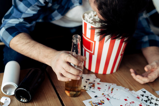 cropped view of man with head in popcorn box holding bottle