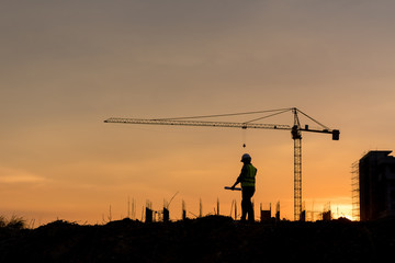 Silhouette engineer construction work control and tower crane background on natural sunset sky.,Heavy industry and building construction work concept