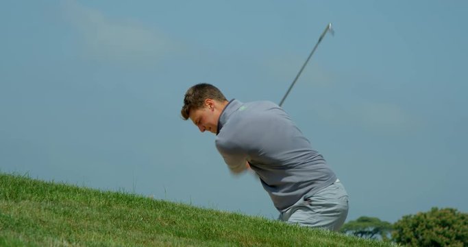 A Golfer plays a great shot out of a sand trap that bounces in front of camera in slow motion.