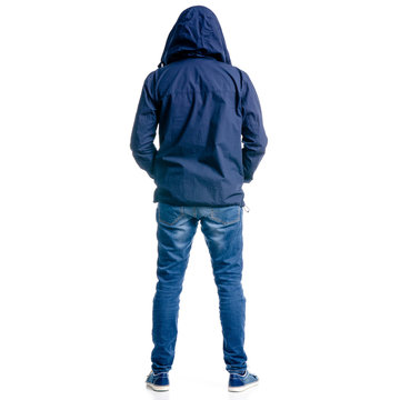 A man in jeans and jacket hood standing looking on white background isolation, back view