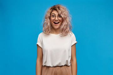 Overjoyed beautiful young woman wearing white oversize t-shirt and round eyeglasses happy to...