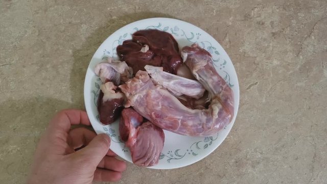 Home cooking - Placing a plate of raw and fresh Turkey odds like neck, heart, liver and gizzard on the plate just after removing from package and picking neck for close up shot..