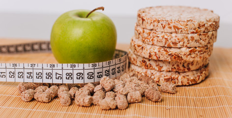 Green apple wrapped with a centimeter, and bran. Healthy food. Diet for weight loss. Dietary bread