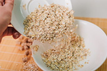 Oatmeal and bran in a white plate. Pour into a bowl. Slimming diet