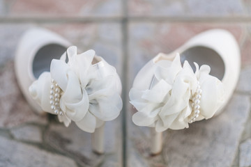 View of white bridal shoes and artificial flowers