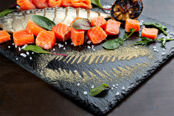 Mackerel, salmon pieces. Laid out on black slate. Beautiful fish cubes.
