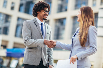 Businessman and businesswomen shaking hands outside office