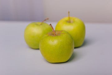 Three green apples lying on a white table. Apple diet