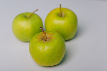 Three green apples lying on a white table. Apple diet