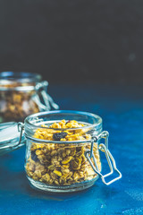 Two open glass jars of organic granola on a dark blue concrete table