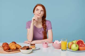 Photo of red-haired girl looking upwards with dissatisfaction, doubts thinks about diet,health,...