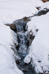 frozen little water stream in winter landscape