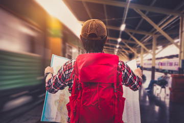 Fototapeta na wymiar Young man wanderer holding a map and searching direction on location map while traveling train station. Tourist searching location concept. Retro style