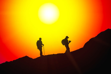 Traveller with a group hiking in the mountains at sunset