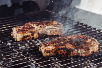 selective focus of juicy tasty steaks grilling on barbecue grill grade with smoke