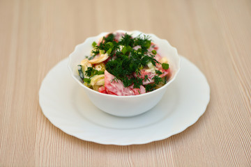 Salad in a plate on a wooden background