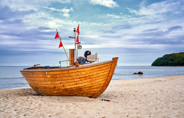 Fototapeta na wymiar Old wooden fishing boat on sandy beach in the Baltic Sea resort of Binz. Island Rügen, Germany