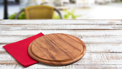 empty pizza board on empty wooden table with tablecloth,napkin - top view