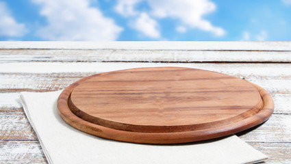 empty pizza board on empty wooden table with tablecloth,napkin - top view