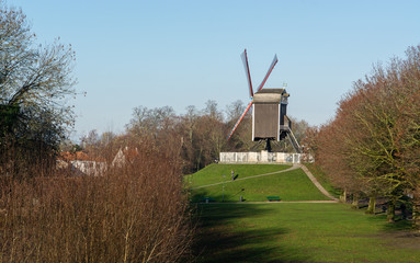 Obraz premium Sint-Janshuismolen windmill on a sunny day with green grass and clear blue sky, Brugge, West Flanders, Belgium