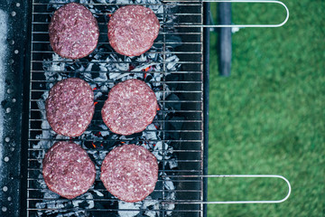 top view of uncooked fresh burger cutlets grilling on bbq grid
