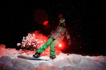 Active female snowboarder dressed in a green sportswear standind on the mountain hill