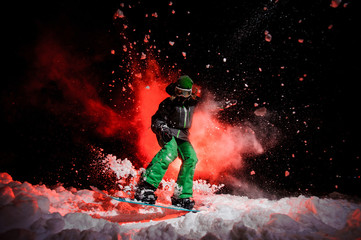 Active female snowboarder dressed in a green sportswear jumping on the snow