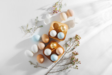 Natural Colored Eggs in wooden egg box and flowers with sunlights. Compositions in pastel colors.  Easter concept.