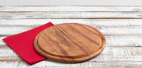 empty pizza board on empty wooden table with tablecloth,napkin - top view