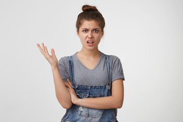 Close up of a young girl looks displeased, indignant, angry, one hand is raised up, one is crossed,...