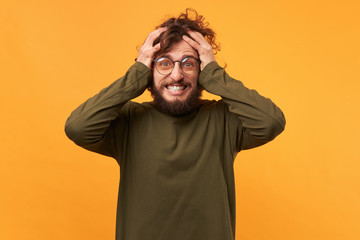 Portrait of a man in glasses with a beard clutched at his head looks glad amazed overwhelmed with...