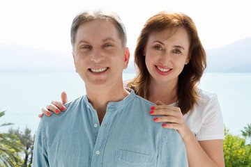 Obraz premium Summer family vacation. Happy middle aged couple having fun on travel holidays weekend. Sea and beach background. Copy space.