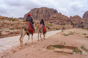 Two bedouins ride camels along the colonnaded street in Petra, Jordan