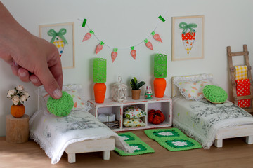 A cozy bright dollhouse bedroom, A woman hand decorating the bed with a knitted pillow