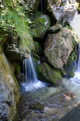 Fototapeta na wymiar Small waterfall between stones covered with moos