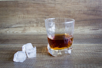 Bourbon Whiskey in a glass with ice on wooden table background